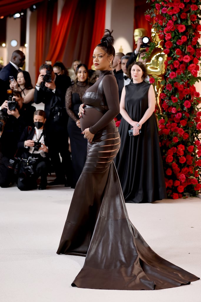 Rihanna revived her luxe maternity style at the 2023 Oscars on March 12. After announcing her second pregnancy during her halftime show at the Super Bowl in February, the "Lift Me Up" singer walked the Academy Awards red carpet in a custom dress with butt-baring hip cutouts by Alaïa. Her stylist, Jahleel Weaver, completed the sheer outfit with satin Giuseppe Zanotti heeled sandals, emerald-and-gold drop earrings by Moussaieff Jewellers, and massive statement rings on each hand.
The proud mom, who famously did not bring her 9-month-old as her date, showcased the sultry dress from all angles as she caressed her baby bump, swaddled in sheer fabric. The gown featured a see-through bodice with a mock-neck collar, long sleeves, and a black leather bralette. A thin strap of leather curved around her back, connecting the top to a floor-length skirt with butt-baring hip cutouts on either side of her waist.
Later in the evening, Rihanna performed "Lift Me Up" in a shimmering lace pantsuit adorned with rhinestone swirls. Around the sheer waist, the ensemble featured crystal panels layered in a feather-like pattern. She paired the outfit with black leather evening gloves and diamond jewelry.
The award show was Rihanna's first public appearance since her viral halftime show, during which she rocked the football field in a Loewe utility jumpsuit. She has since appeared on the cover of Vogue and spoken about what it was like to bring her son home for the first time, as well as how she's cultivating her postpartum style.
Ahead, see Rihanna's stunning dress at the 2023 Oscars.

    Related:

            
            
                                    
                            

            All the Stunning Celebrity Couples at the 2023 Oscars