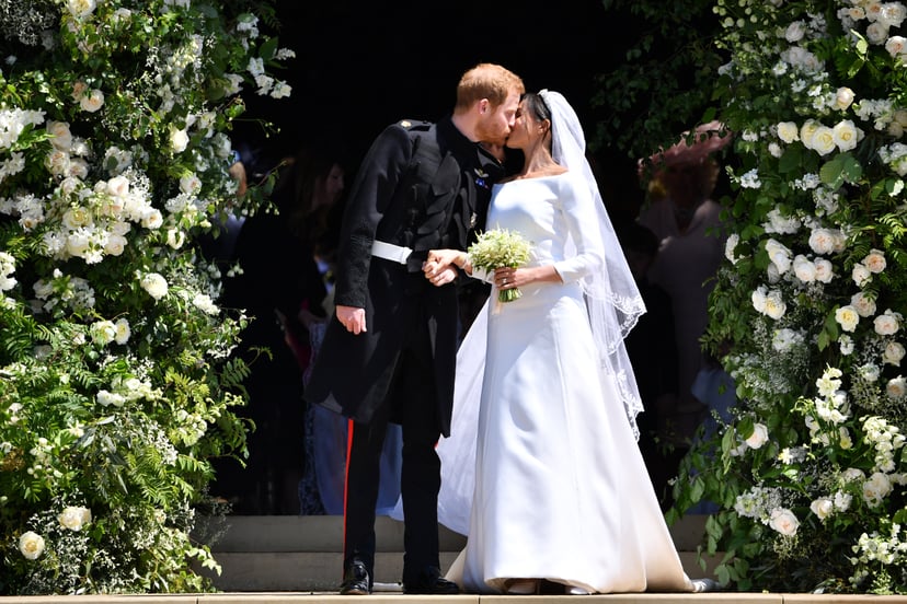 WINDSOR, UNITED KINGDOM - MAY 19: Britain's Prince Harry, Duke of Sussex kisses his wife Meghan, Duchess of Sussex as they leave from the West Door of St George's Chapel, Windsor Castle, in Windsor on May 19, 2018 in Windsor, England. (Photo by  Ben STANS