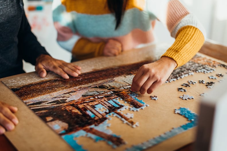 Close up shot of the hands of a couple doing a jigsaw puzzle in their kitchen, shot from in front