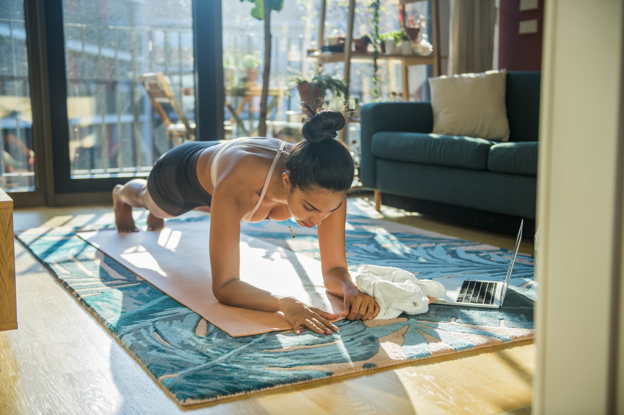 Young woman doing planks in her colorful living room, example of a hard stop exercise.