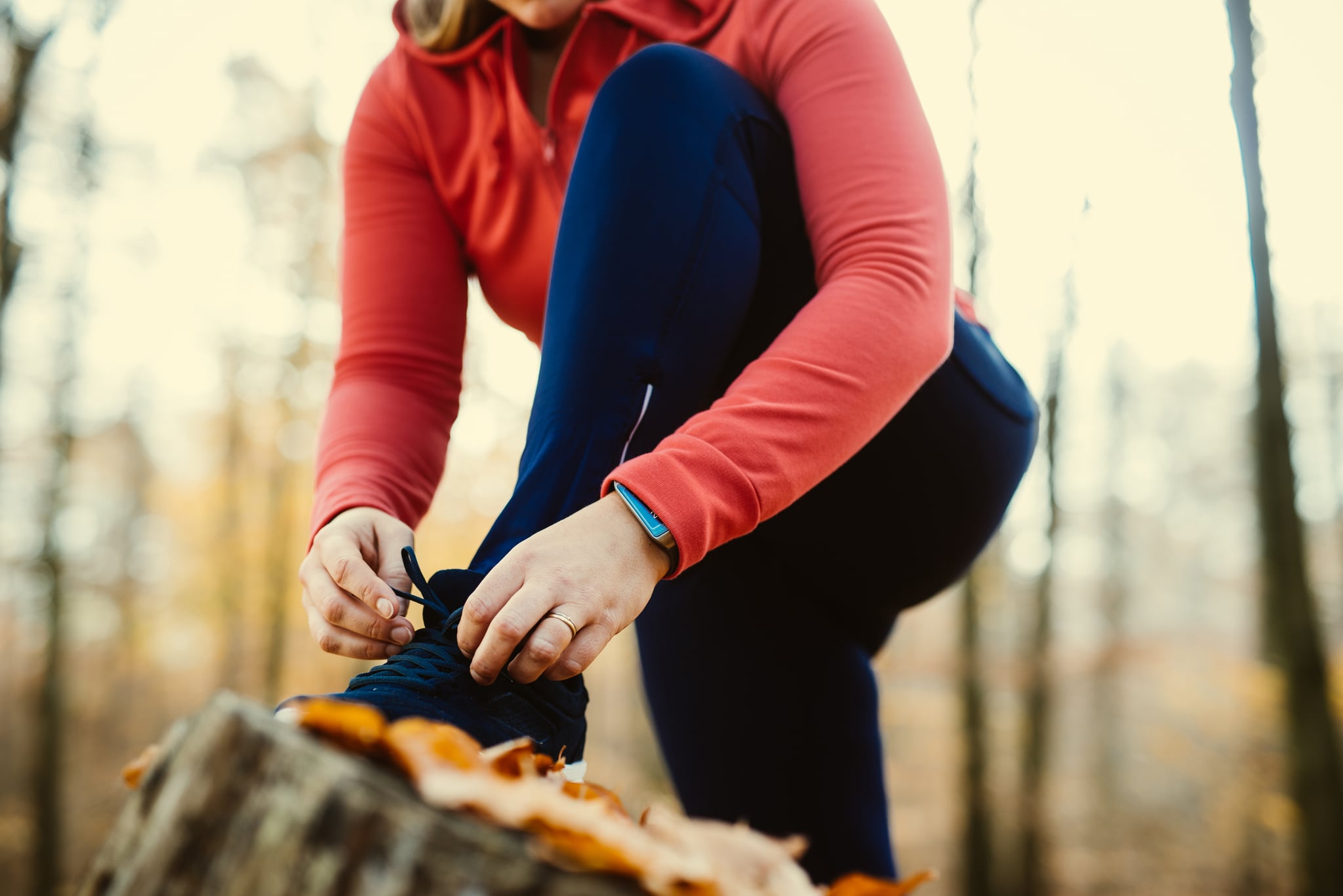Woman fixing her shoelaces before jogging on a trunk.