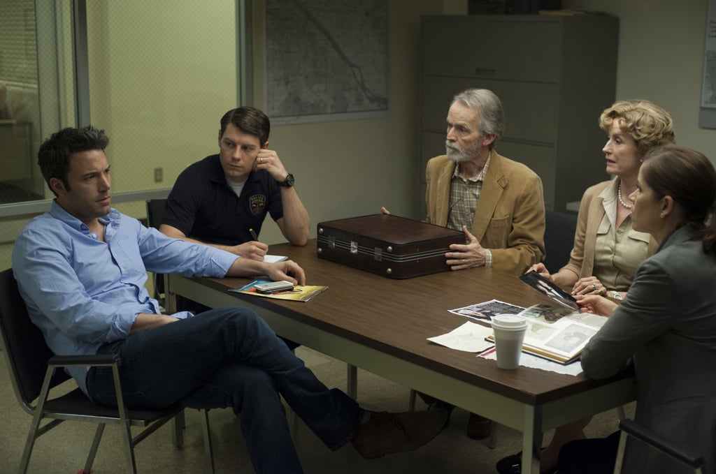 Nick confers with Detective Gilpin (Patrick Fugit) and Amy's parents (David Clennon and Lisa Banes).