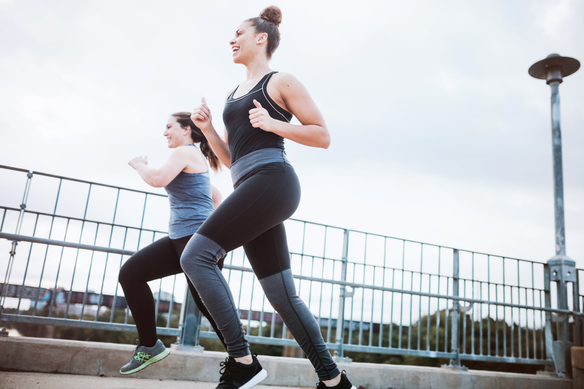 To young adult multi ethnic friends goes for a morning run, crossing the Lamar Street pedestrian bridge in Austin, Texas.  The bridge gets a large volume of foot traffic in the morning with people exercising at the start of their day. They smile as the talk to each other.