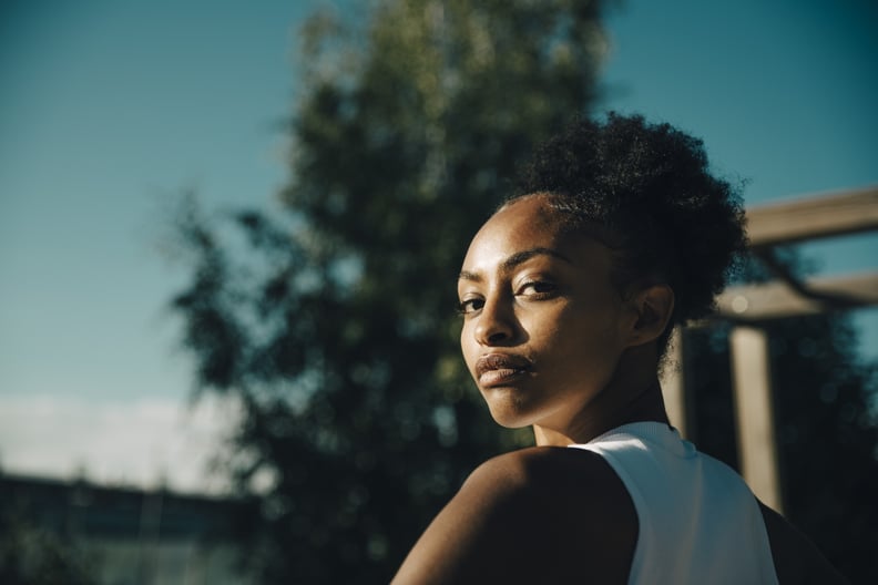 Young woman standing outdoors and looking confidently over her left shoulder.