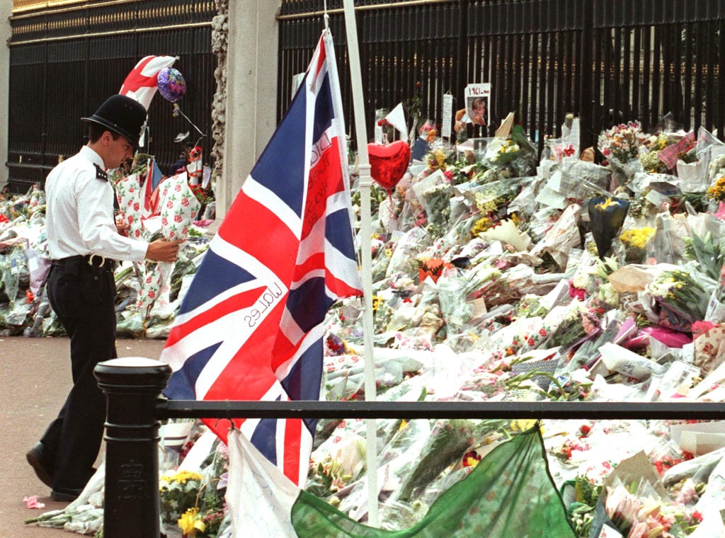 A British bobby carried flowers to the Buckingham Palace gate.