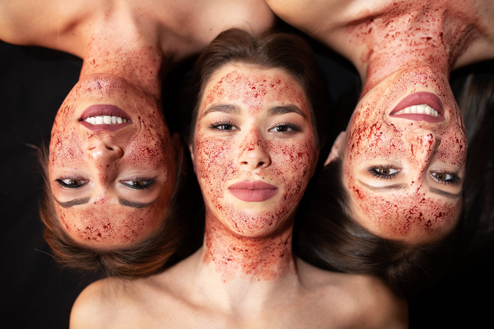 Young women with blood on their faces being used as a beauty treatment