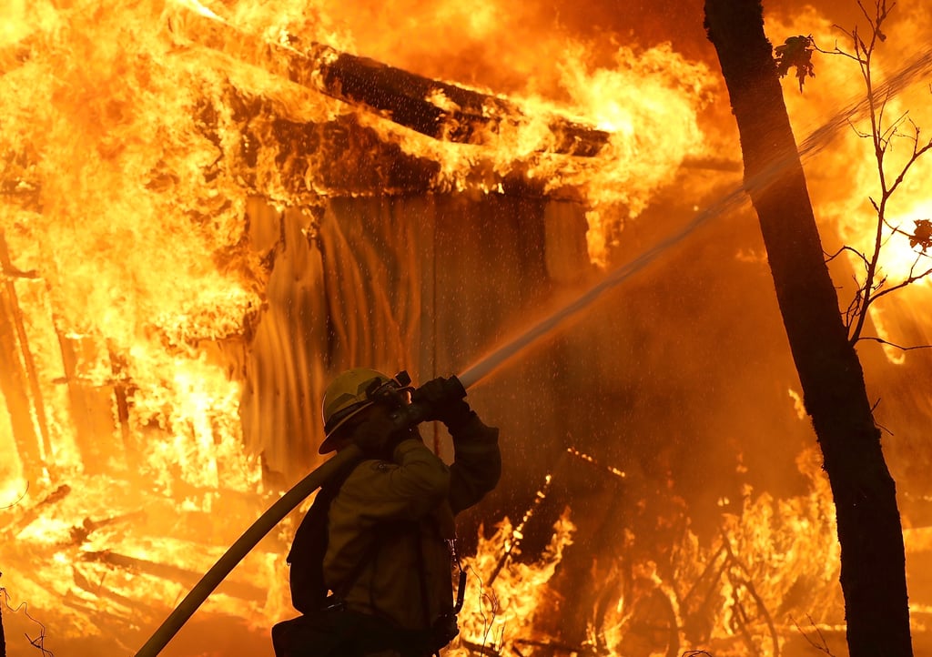 A California firefighter monitors one of the 7,000 structures destroyed by the Camp Fire.