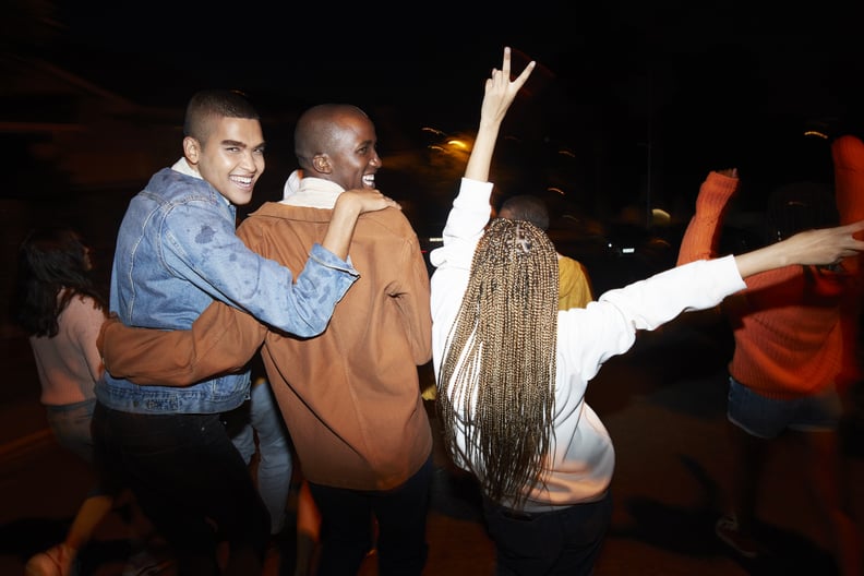Cheerful young males dancing with multi-ethnic friends at night