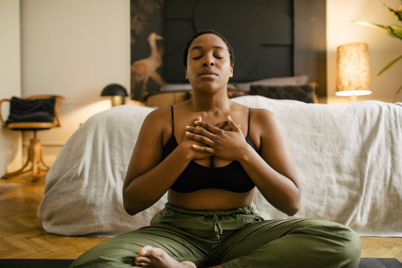 Woman in a seated position with both hands on her chest, practicing non-performative yoga.