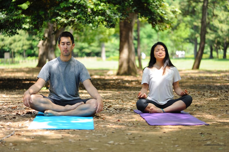 Two people meditating in the park on a sunny day.