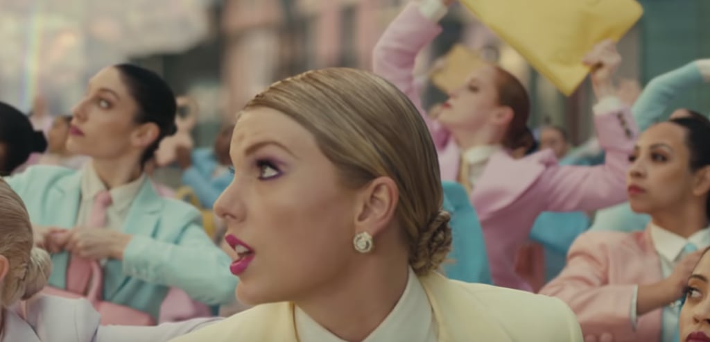 Swift goes for a slightly more pink-hued lip and chooses a side-swept updo to complement her pastel pantsuit.