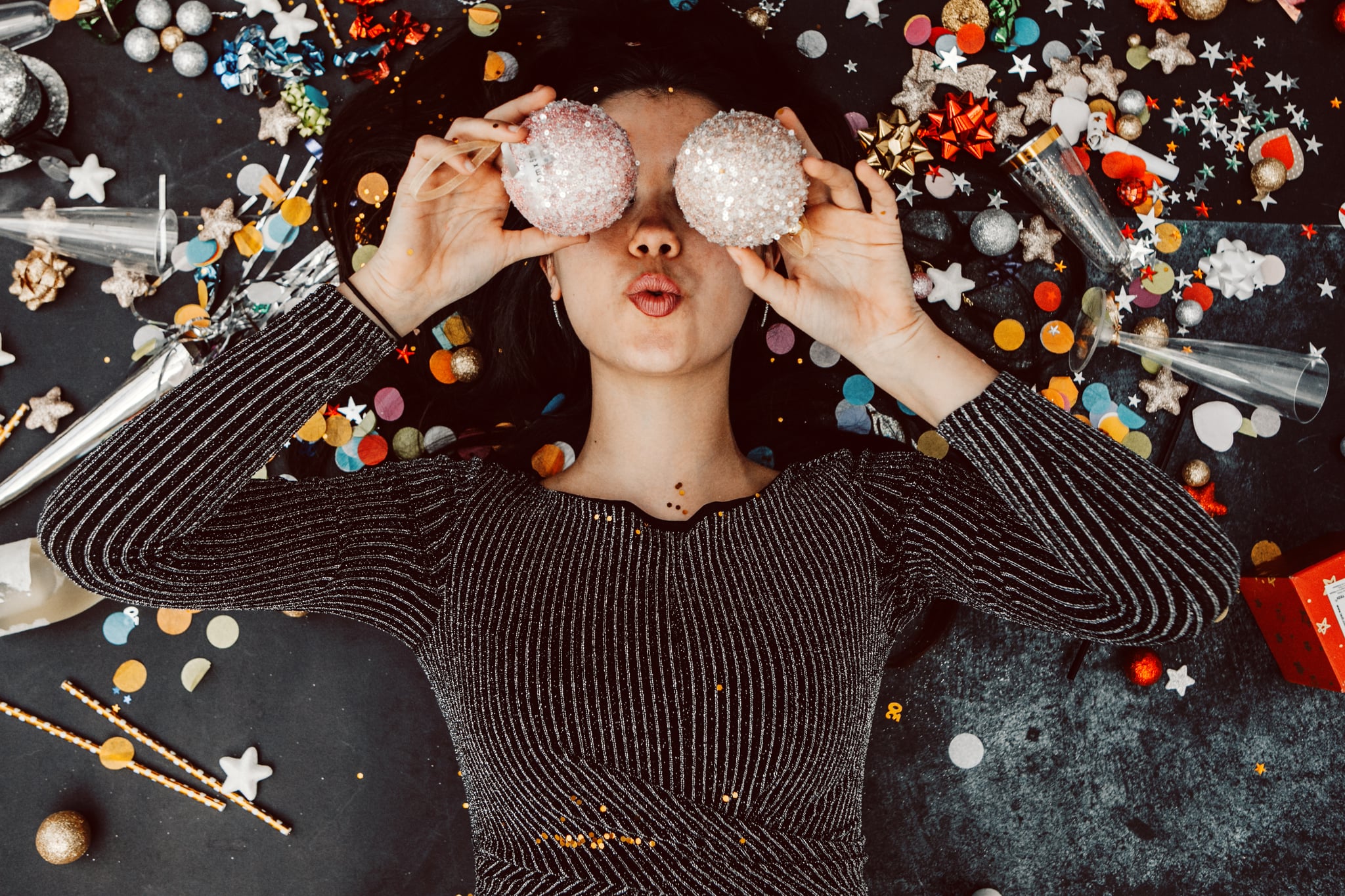 young woman in party dress holding xmas ball in front of eyes