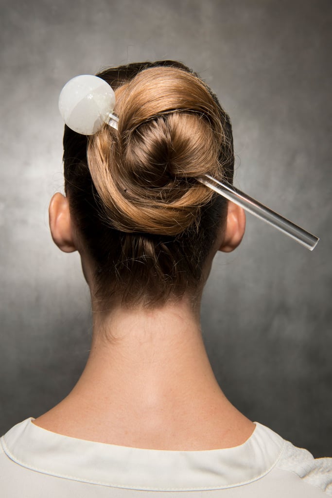 While the models didn't actually wear this giant hair pin while walking down the runway for Pamella Roland, it's still a great way to keep your hair in this twisted bun IRL, although there's no need to use such a statement accessory like the one pictured. Instead, use any lengthy pin (even a chopstick could work!) to pull your hair into a ponytail, twisting it until it begins to spin into a ballerina-bun shape and securing it with a pin. As a bonus, with your hair folded up into itself like that, you'll be setting yourself up for the perfect bun drop video (if you feel so inclined).