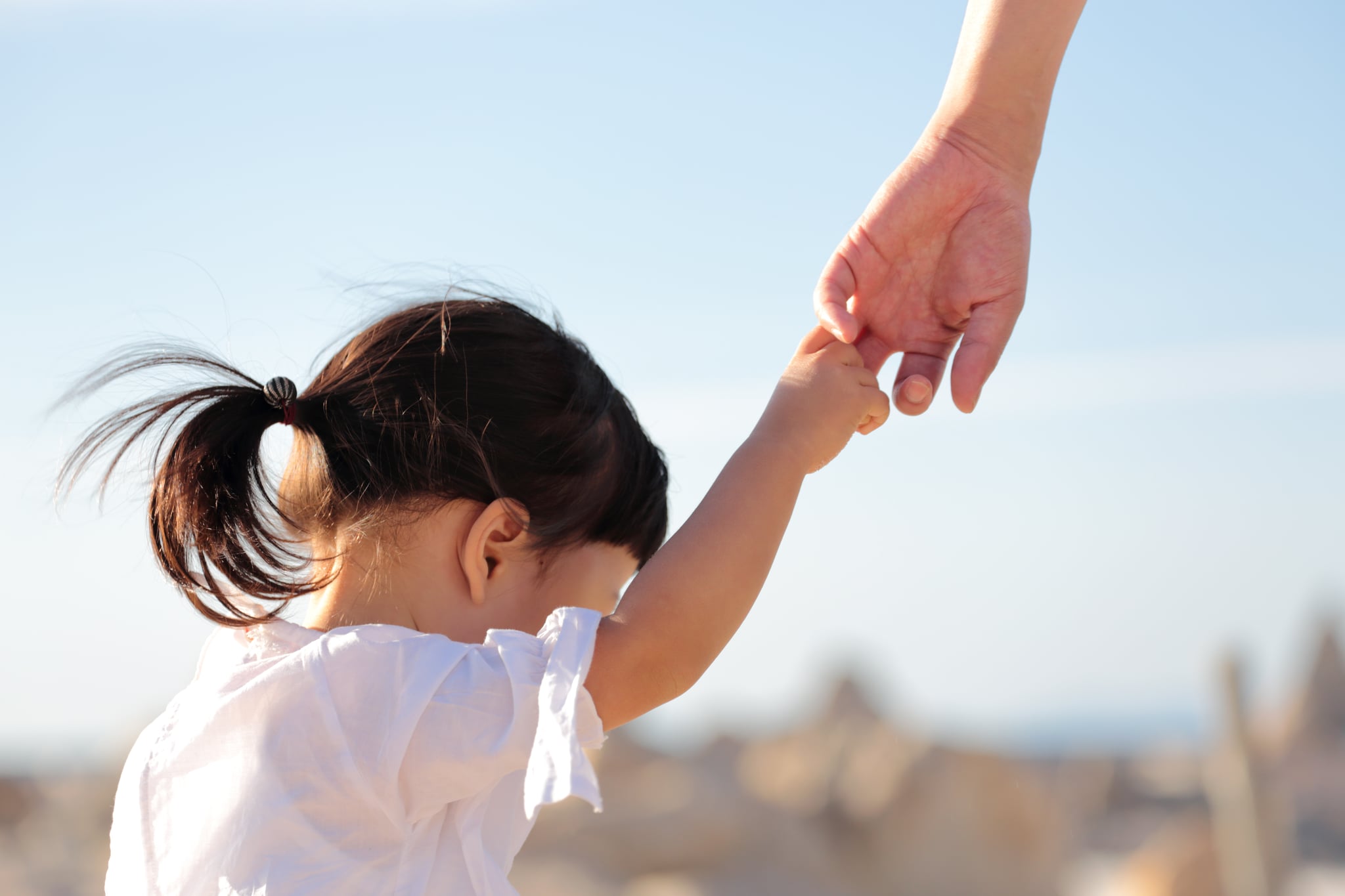 Father and 1 year and 10 months old daughter walking hand in hand on beach in Wakayama