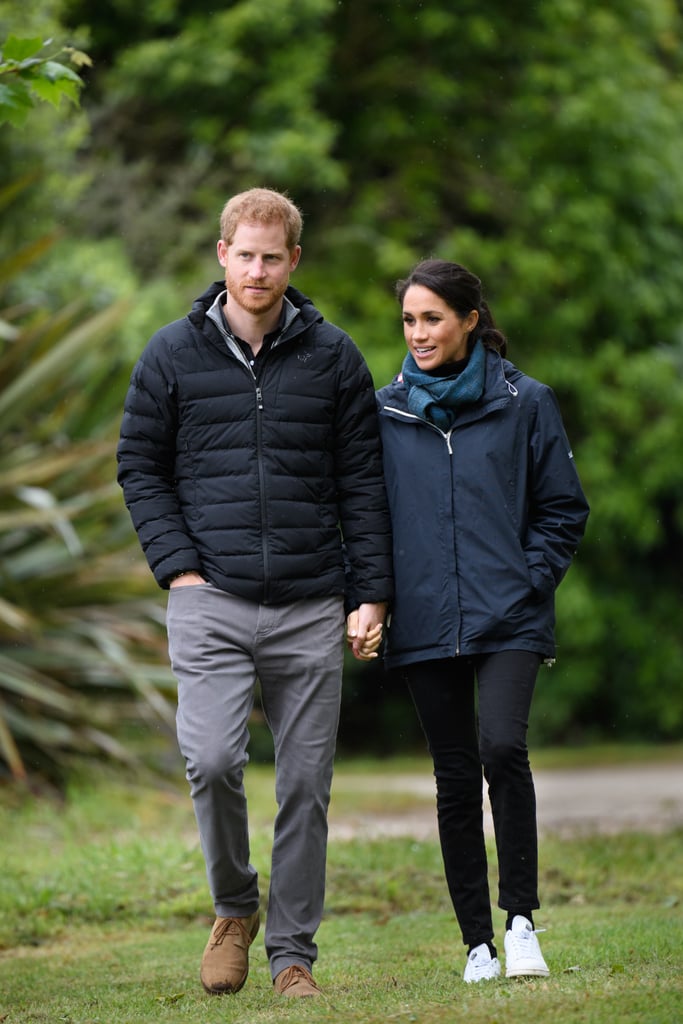 While in New Zealand, the Duchess of Sussex wrapped up in a raincoat, which she paired with black jeans, a scarf, and comfortable white trainers by Stella McCartney for Adidas.