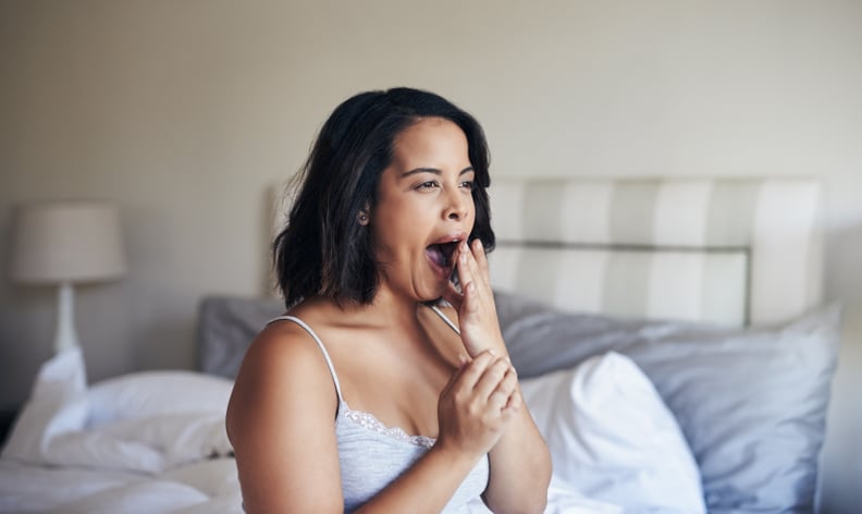 Shot of a young woman waking up in bed in the morning and yawning