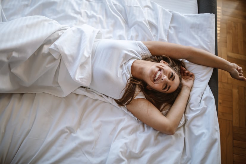 Young beautiful woman waking up rested and refreshed in bedroom