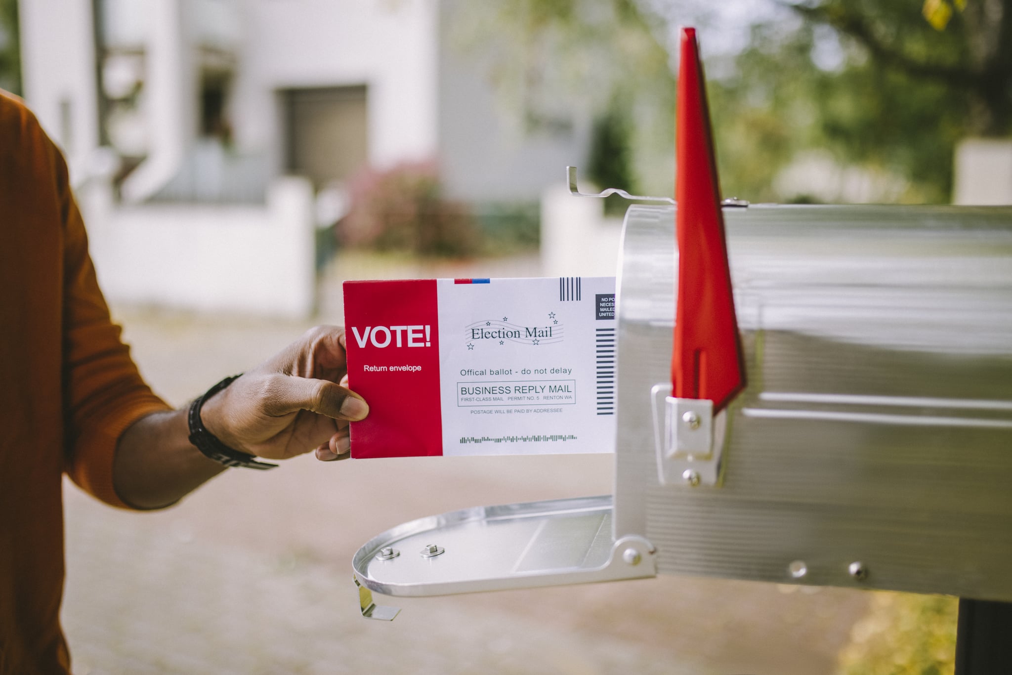 Close up of hand putting voting ballot to mailbox.