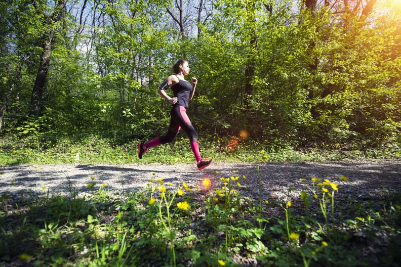 A young woman running in the forest footpath.