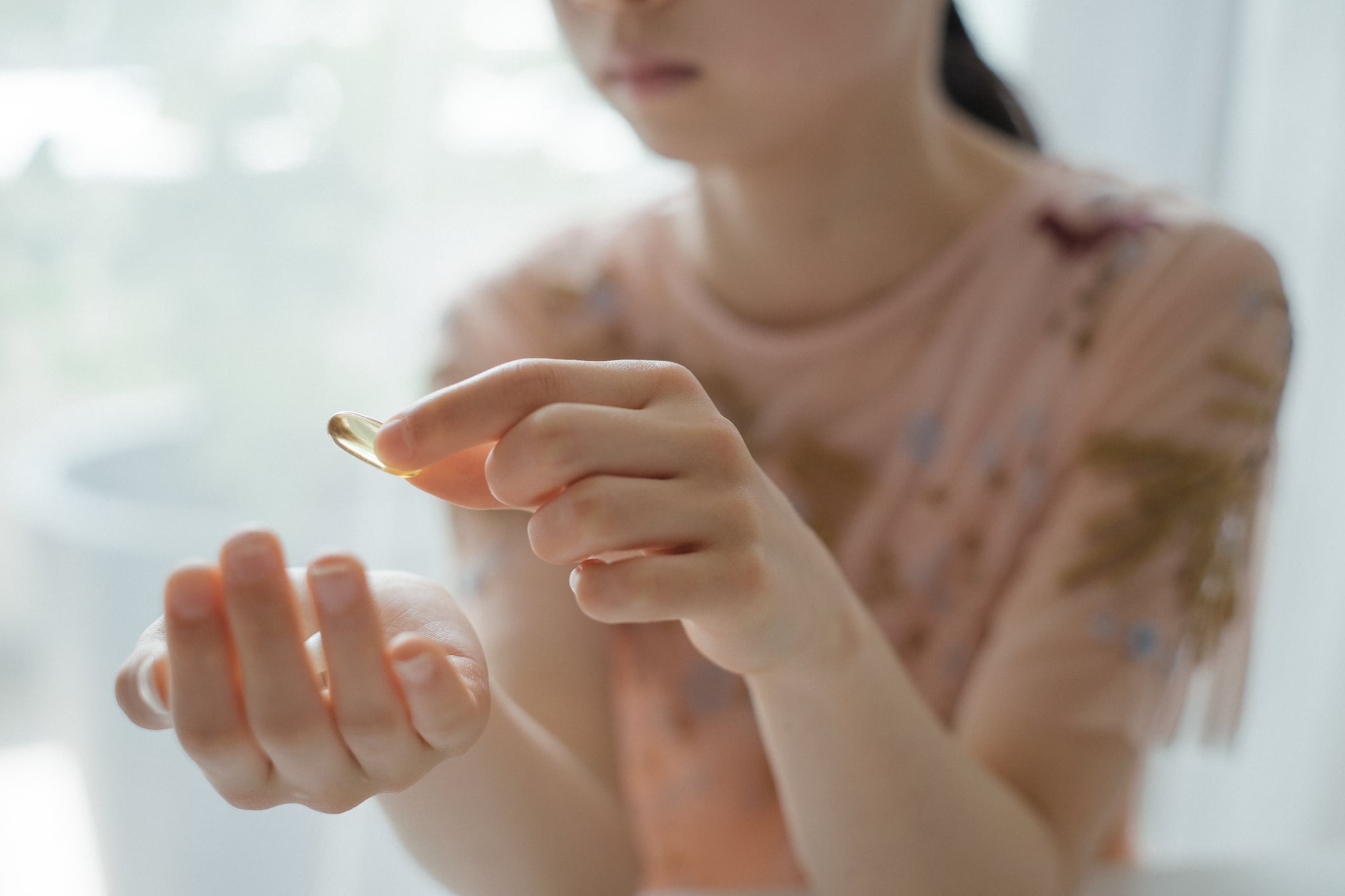 Girl taking a vitamin or omega-3 supplement capsule.