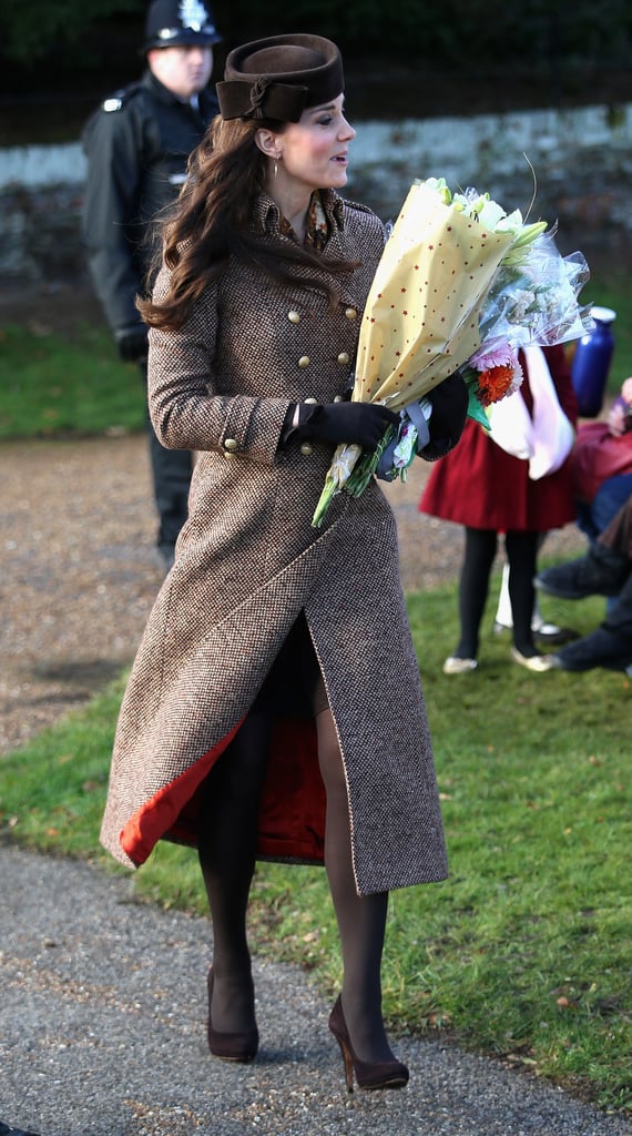 In 2014, Kate wore Moloh's Turpin coat, which featured scarlet interior lining. The duchess wore tights and a Betty Boop Lock & Co. hat. She tucked a Really Wild Clothing printed scarf under her outerwear and accessorized with Imogen gloves, Catherine Zoraida gold earrings, and suede Emmy pumps.