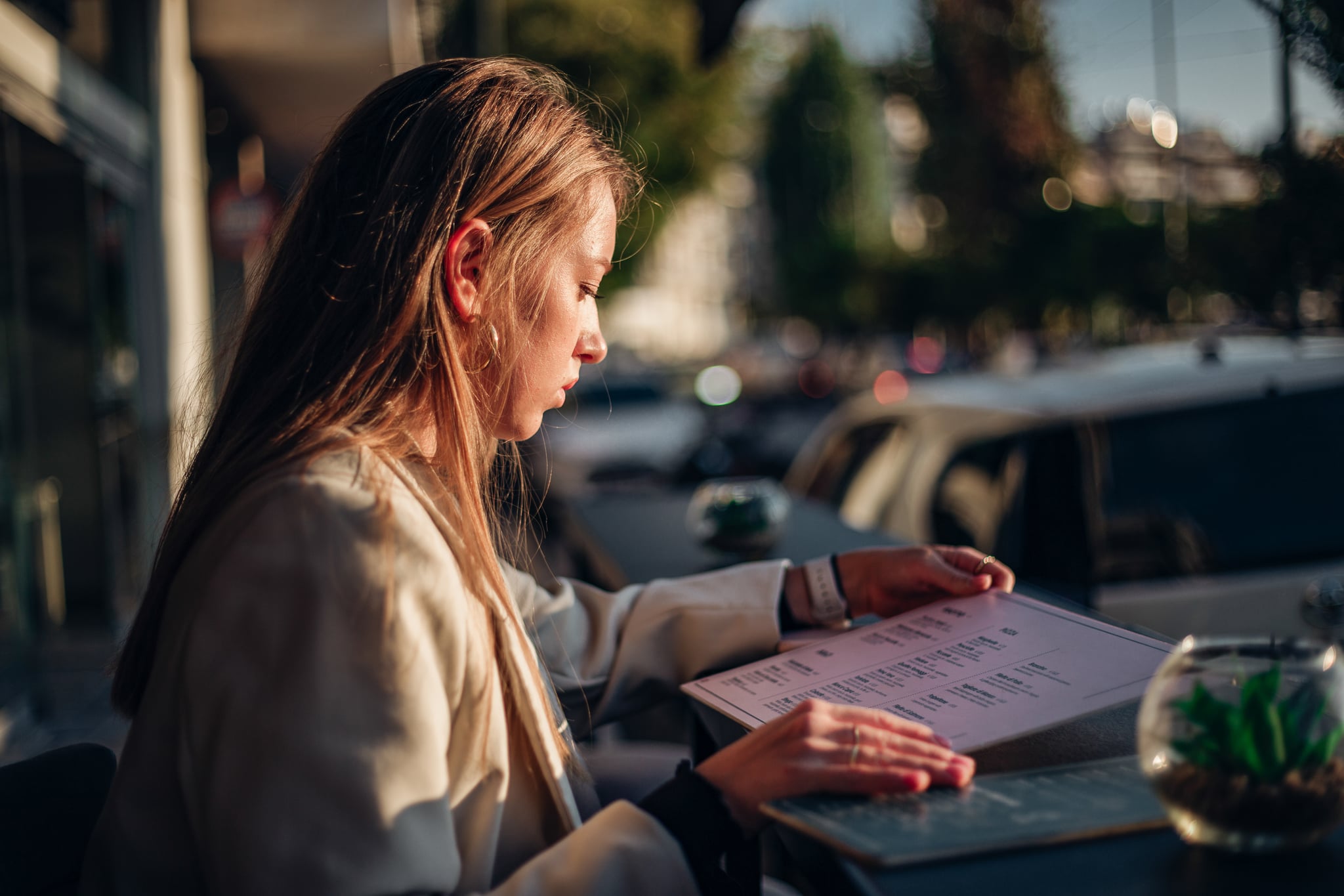 Young woman looking at the menu while eating outdoors.