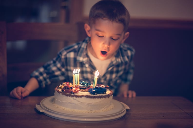 little boy blowing out candles on his car, birthday cake