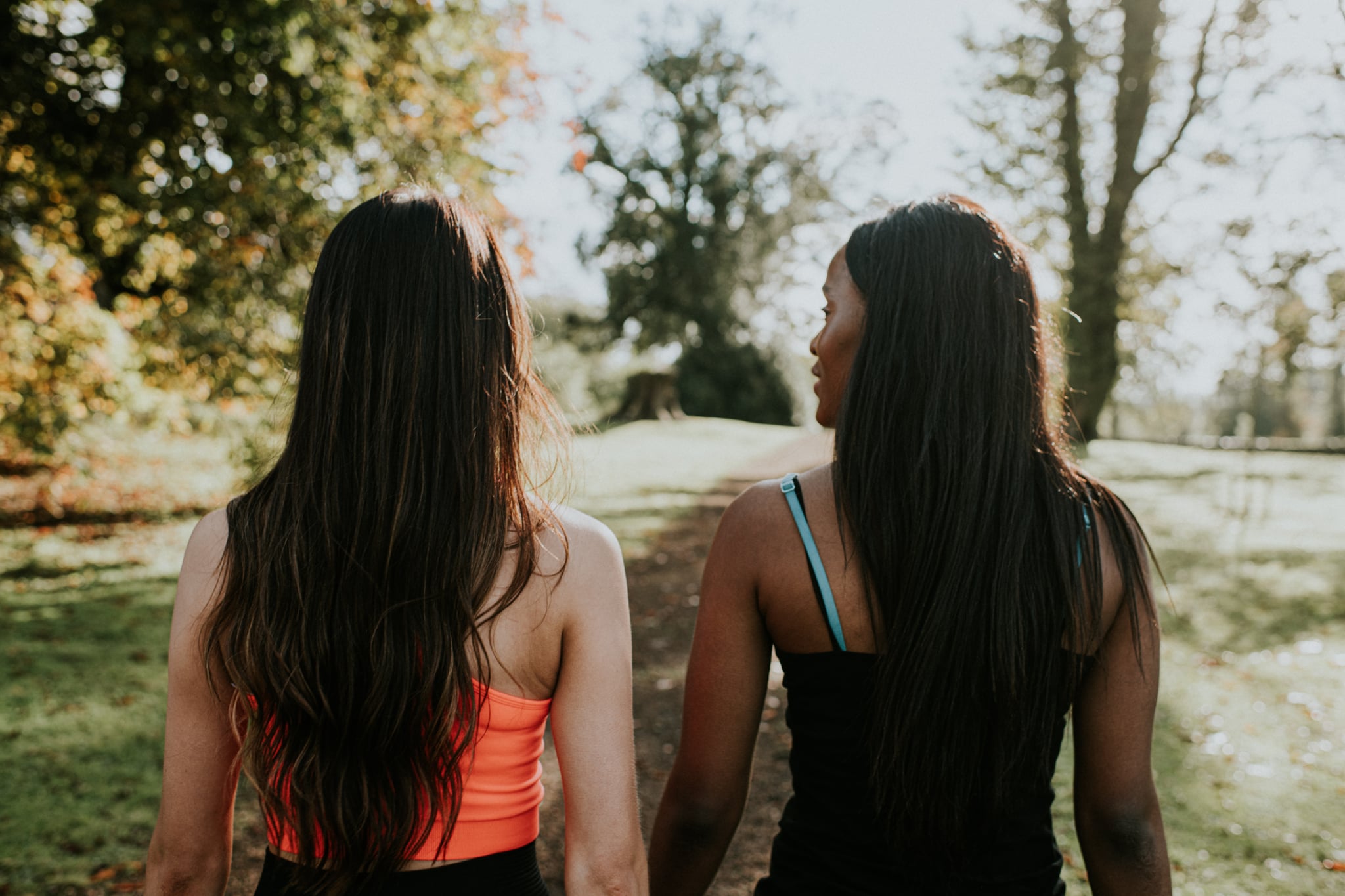 Two woman walking through a sunny park together 