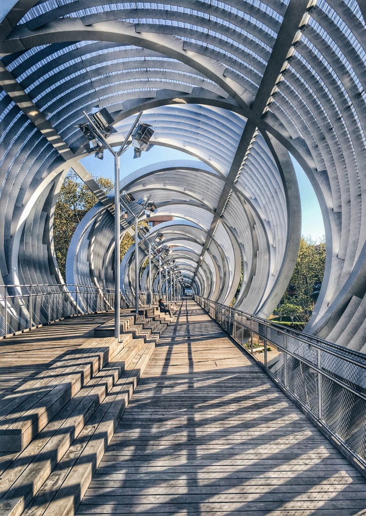 Another must-see attraction is the Arganzuela Footbridge. Uniting the two banks of the Manzanares River, this spiraling and conical bridge is dedicated to pedestrians and cyclists. Originally built to improve the urban connections between the north and south neighborhoods of Madrid, this footbridge has quickly become an iconic landmark within the city.
Another must-see attraction is the Arganzuela Footbridge. Uniting the two banks of the Manzanares River, this spiraling and conical bridge is dedicated to pedestrians and cyclists. Originally built to improve the urban connections between the north and south neighborhoods of Madrid, this footbridge has quickly become an iconic landmark within the city.