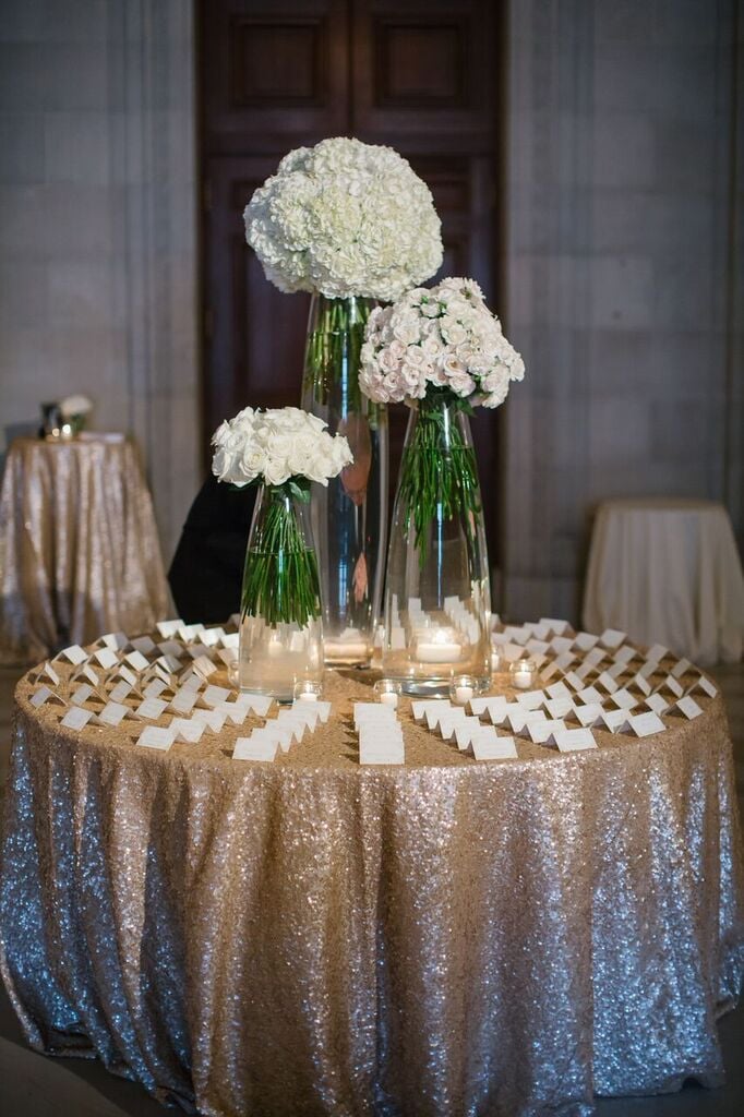 Guide guests to the place card table with an asymmetrical floral arrangement and glittery tablecloth.