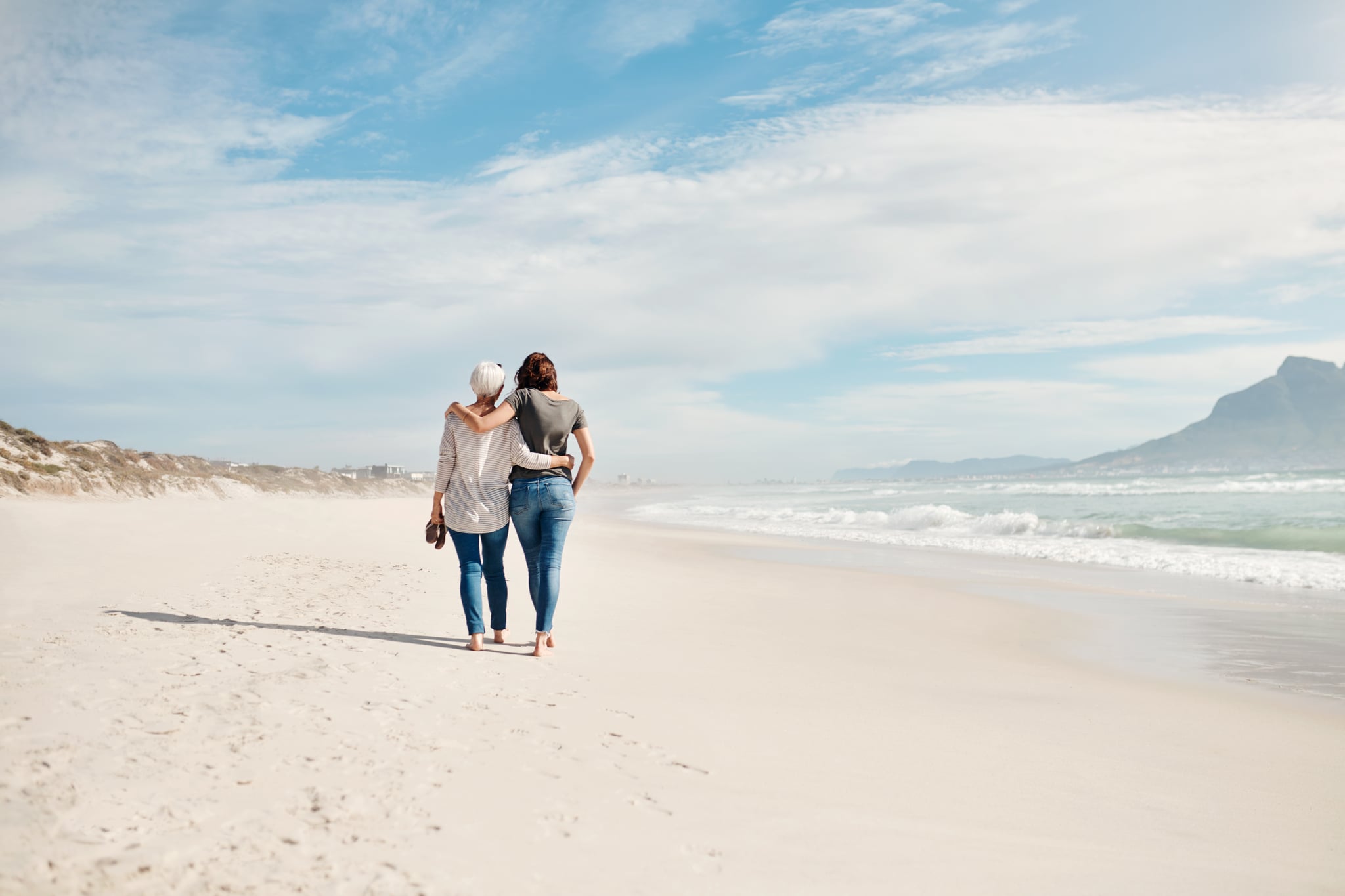 Rearview shot of a young woman going for a walk along the beach with her elderly mother