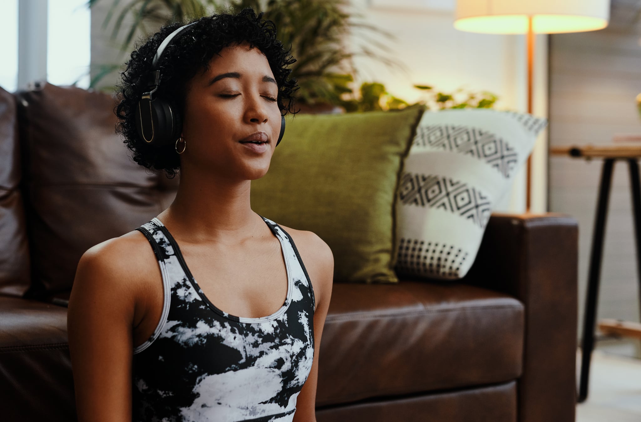 Shot of a young woman listening to music while meditating at home