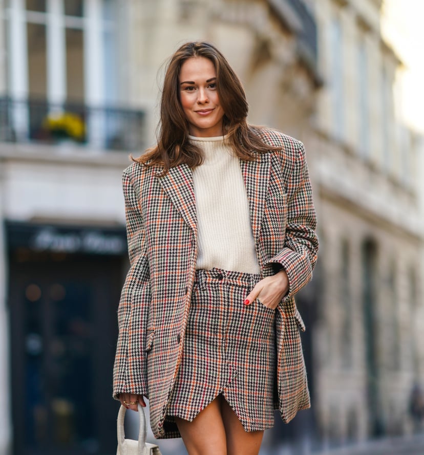PARIS, FRANCE - NOVEMBER 28: Therese Hellström wears a full Zadig & Voltaire look made of a white wool pullover, a checked houndstooth pattern oversized blazer jacket with long sleeves, a short slit skirt, a white Jacquemus bag made of fabric, burgundy le