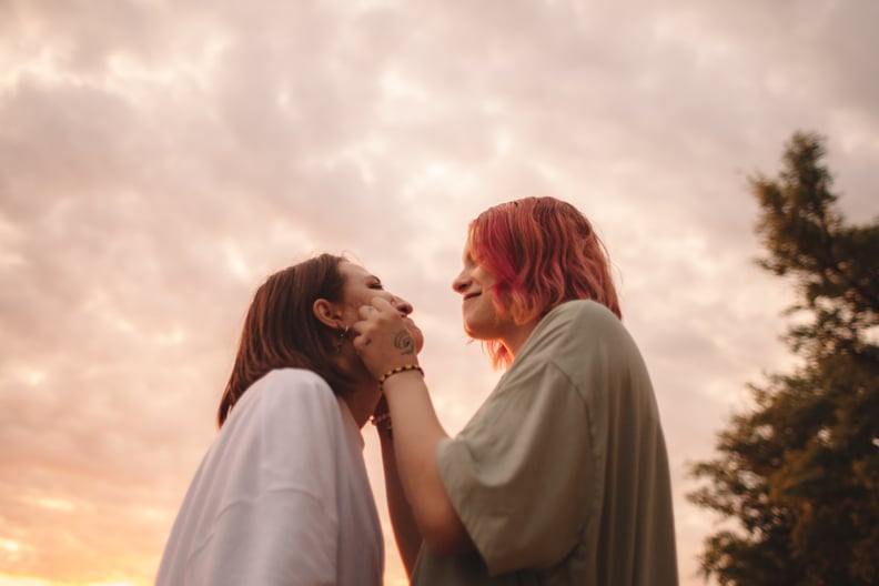 young woman touching her girlfriends cheeks at sunset