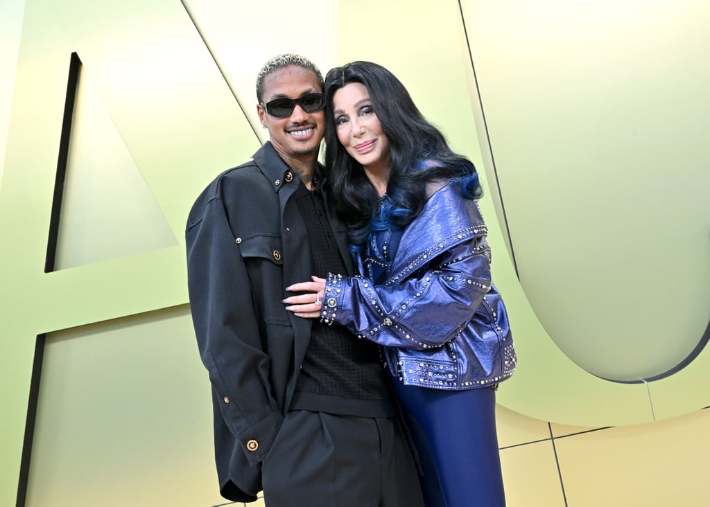Cher and Alexander Edwards are red-carpet official. The couple attended the Versace fall 2023 fashion show in Los Angeles on March 9, sharing a sweet kiss while posing for photos at the star-studded event. Cher, 76, seemingly confirmed her relationship with the 37-year-old music executive back in November 2022, when the two held hands on a dinner date. They've been inseparable since, even sparking engagement rumors a month later when Edwards gifted Cher a diamond ring. 
"THERE R NO WORDS," the singer tweeted at the time, sharing a photo of her ring. Cher didn't elaborate on the ring's exact significance, and her reps did not respond to POPSUGAR's request for comment. Wedding bells aren't ringing just yet, however, according to People. "They're not talking marriage or anything like that, but they are exclusive and serious," a source told the publication. That said, Cher put the ring on display yet again at the Versace show, holding it up against Edwards's chest, the diamond shining against her bejeweled jacket.
More recently, Cher and Edwards also attended a Super Bowl party together, spending a weekend in Arizona with several other stars. "On paper, it's kind of ridiculous," Cher said on "The Kelly Clarkson Show" in December 2022, referencing the age gap between them. "But in real life, we get along great. He's fabulous. And I don't give men qualities that they don't deserve." 
Cher added, "Maybe younger men don't care if you're funny or outrageous and want to do stupid things and you have the strong personality. I'm not giving up my personality for anybody, OK?" Read on to see the pair hit the red carpet for the first time together. 
Related:
Brendan Fraser Hits the SAG Awards Red Carpet With Girlfriend Jeanne Moore