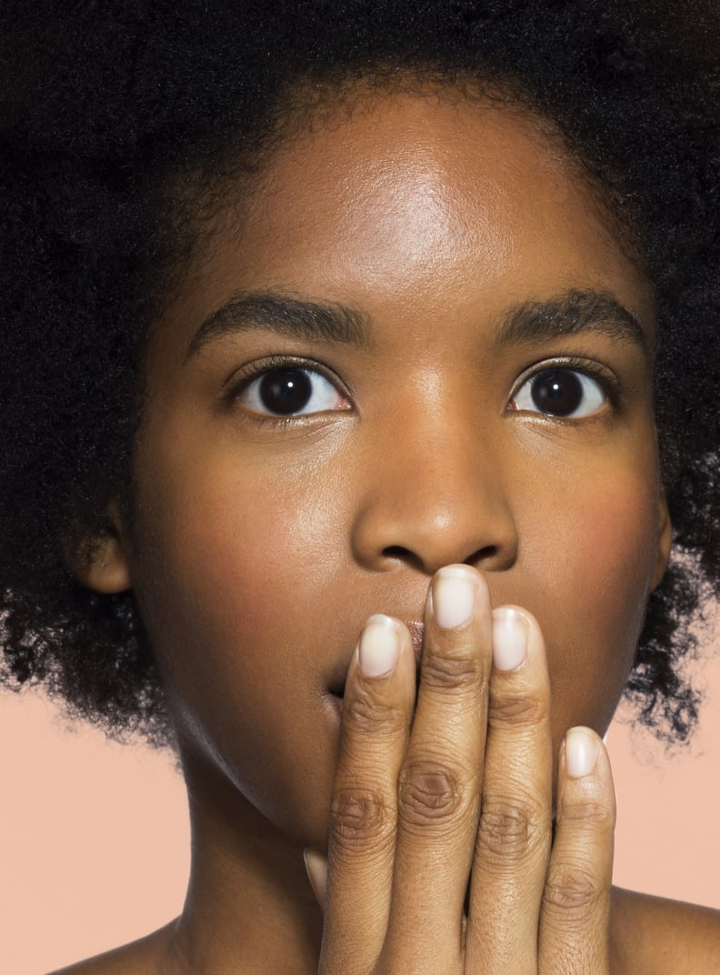 Young mixed-race female covering mouth thinking with pink background