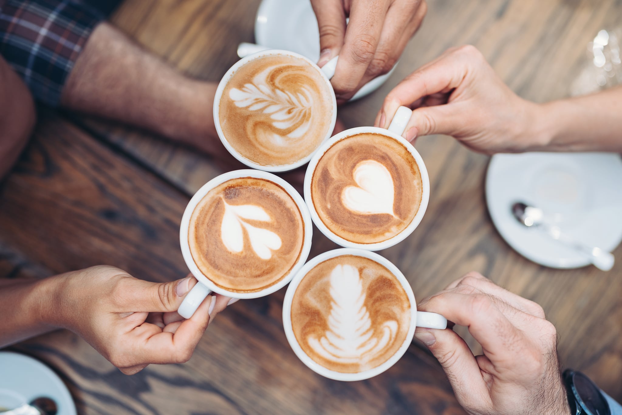 Above view of hands holding cappuccino cups