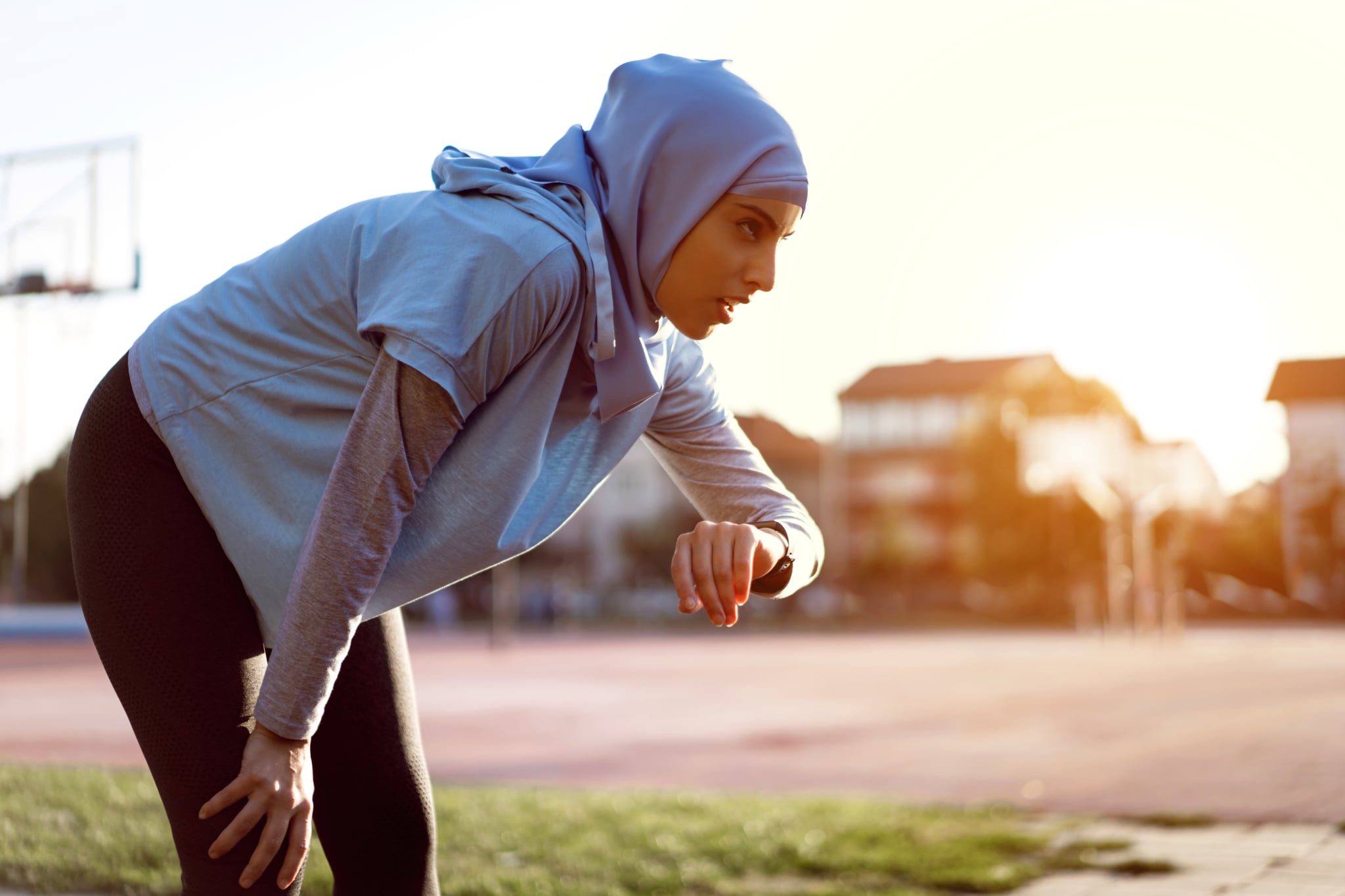 Femme musulmane fatiguée, athlète d'athlétisme mesurant sa trace de fréquence cardiaque avec un tracker de fitness après avoir terminé l'entraînement