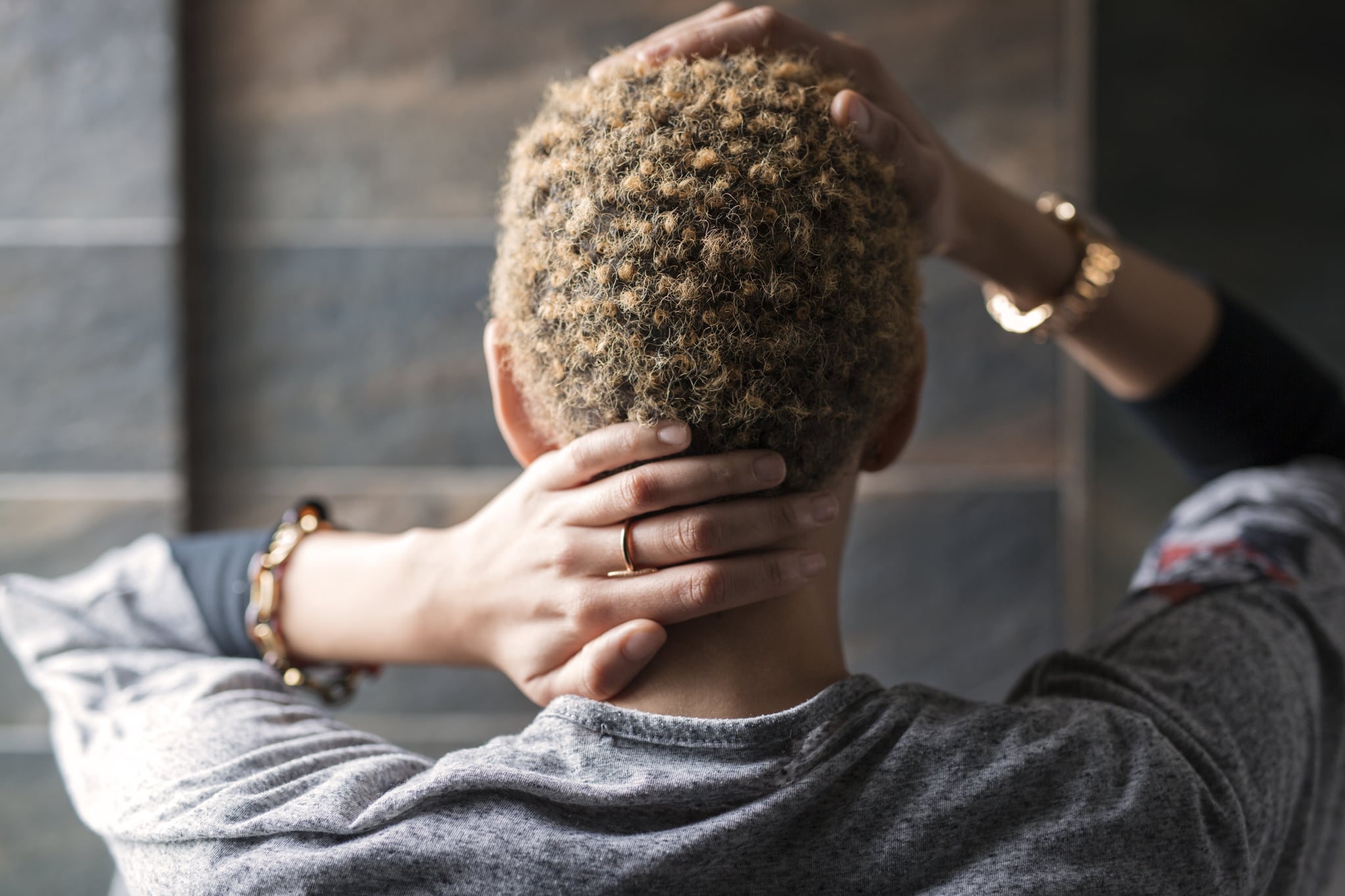 Woman with blonde short hair rubbing her head.