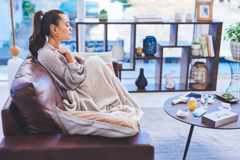 Cropped shot of an attractive young woman sitting alone on her sofa at home and feeling sick