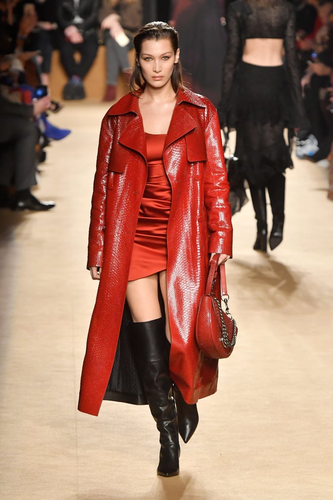 At Roberto Cavalli wearing a red trench coat and minidress.