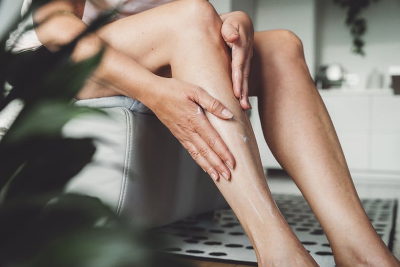 Caucasian woman applying body lotion, massaging it on her legs. Adult woman using body lotion.