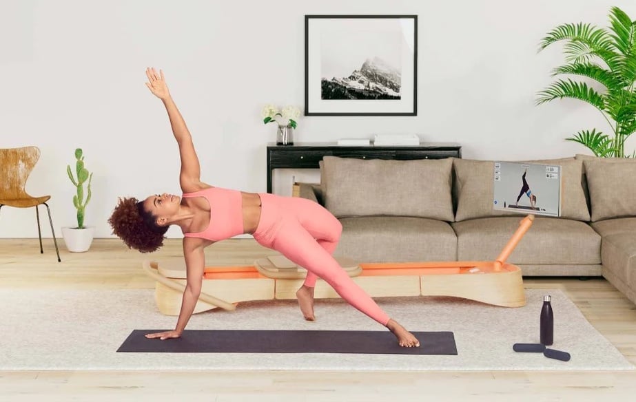 Woman using the Frame Pilates reformer in her home