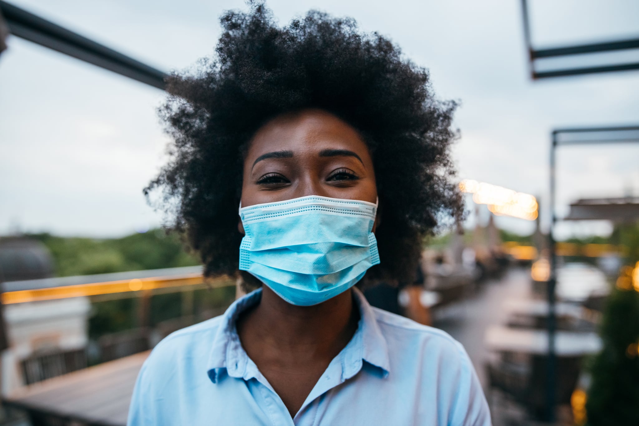 Portrait of young businesswoman looking at camera and smiling behind the mask.