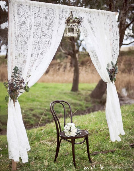 Dainty lace curtains, natural arrangements, and a delicate white birdcage create a rustic, elegant vibe.
Photo by Mile Photography via Style Me Pretty