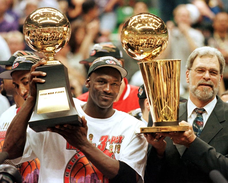 (FILES) In this 14 June 1998 file photo, Michael Jordan (L) holds the NBA Finals Most Valuable Player trophy and former Chicago Bulls head coach Phil Jackson holds the NBA champions Larry O'Brian trophy 14 June after winning game six of the NBA Finals wit