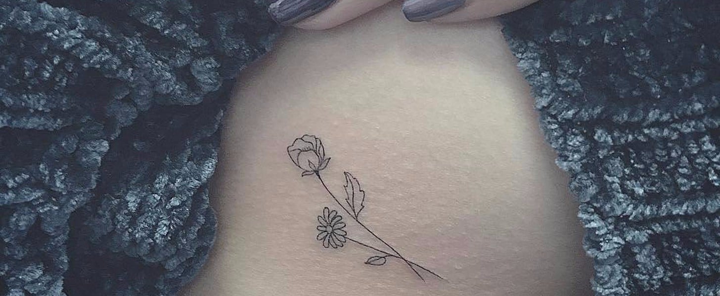 Fine line flower tattoo on the side boob.