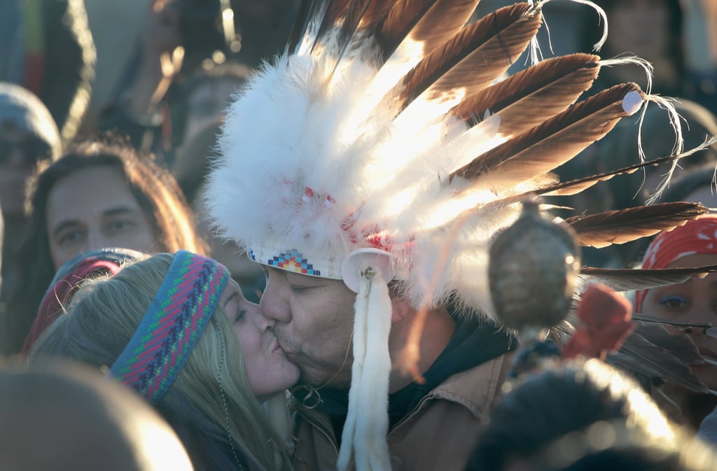 Two protesters in a crowd share a kiss.