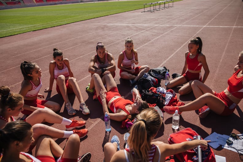 Young athletics team on a sports stadium, enjoying time together after training.