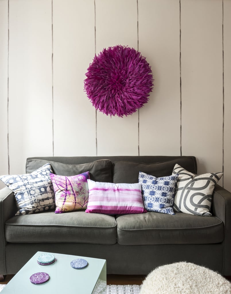 To maximise space, Ali and Lindsay choose side and coffee tables that double as stools for additional seating. To add personality, they hung a magenta juju (African feather headdress) above the sofa. Photo by  Matthew Williams via LABLstudio 